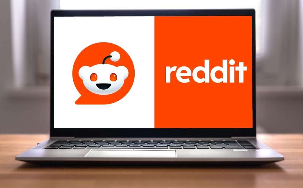 A laptop displaying the Reddit logo and the word reddit in white on an orange and white background, highlighting how reddit for digital marketing can be a powerful tool for brand visibility.