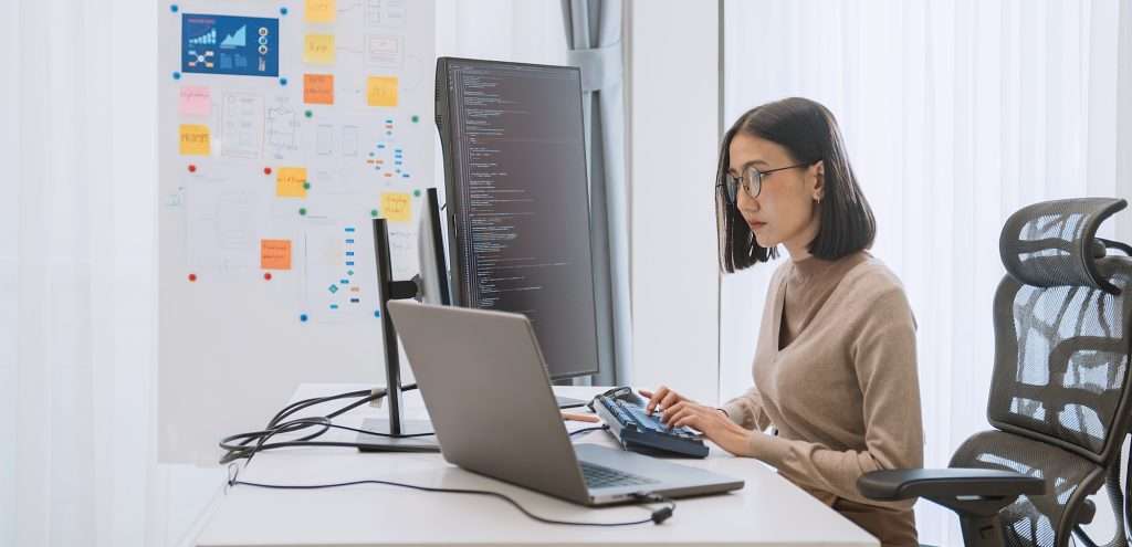 young adult marketing professional looking at multiple computer screens